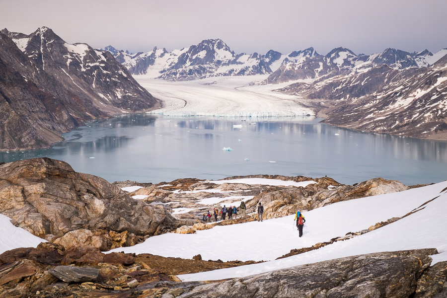 Trekking group descending towards Karale Fjord with Knud Rasmussen Glacier and mountains in the background