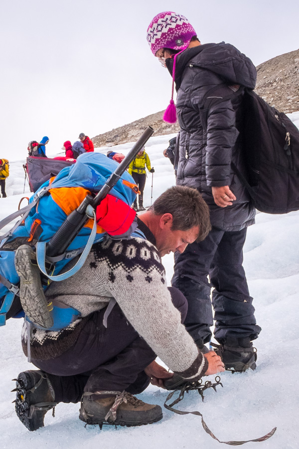 Maxime kneeling down on the unnamed glacier to adjust the crampons of one of my trekking companions