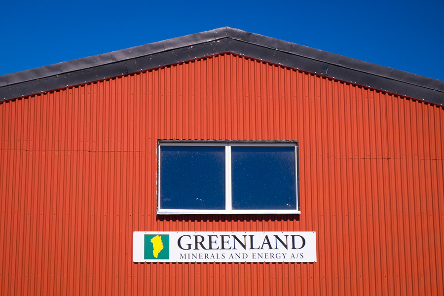 Red shed in Narsaq with a sign for Greenland Minerals and Energy and an outline of Greenland