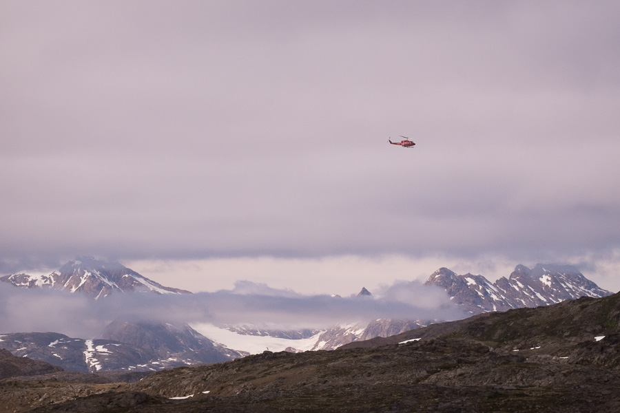 An Air Greenland helicopter flying below the low cloud to transfer passengers from Tasiilaq to Kulusuk in East Greenland