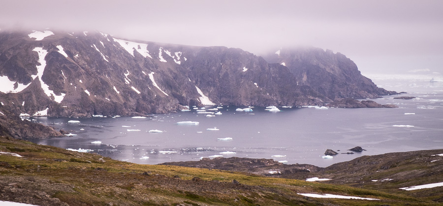 Icebergs in the ocean and very low cloud. Seen while hiking from Kulusuk to Isikajia in East Greenland