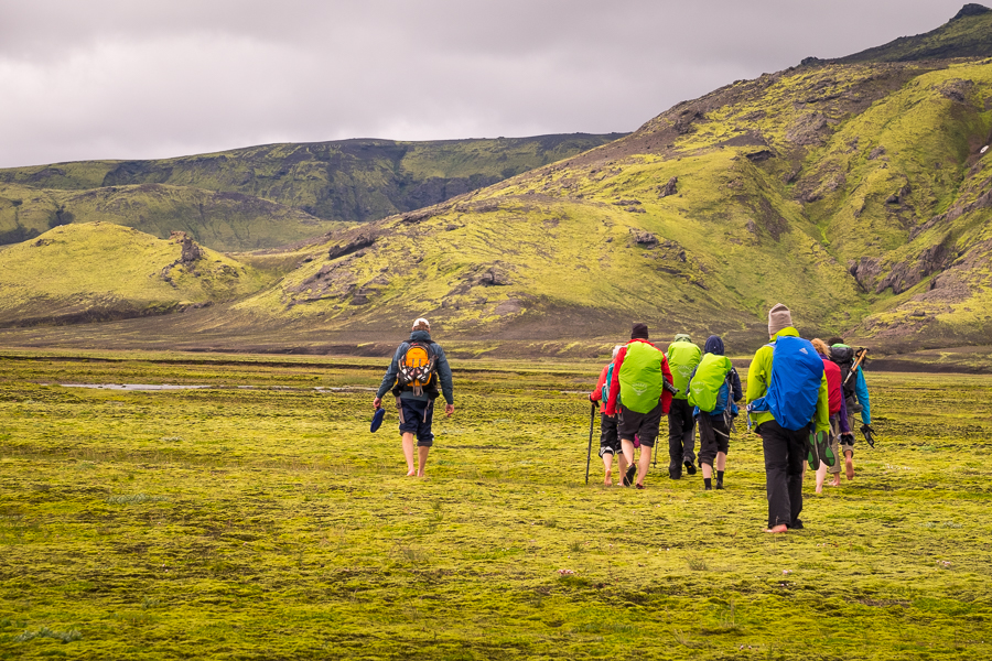 Trekking companions walking barefoot between the river channels - Volcanic Trails - Central Highlands, Iceland