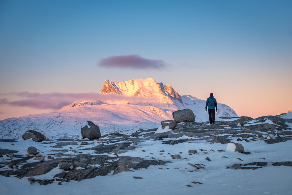 Hiker at a viewpoint of Sermitsiaq mountain which is glowing in the late afternoon sun - Nuuk - West Greenland