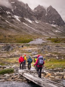 Trekking companions crossing a very dilapidated bridge over the river