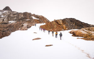 Trekking group following muddy bootprints in the snow