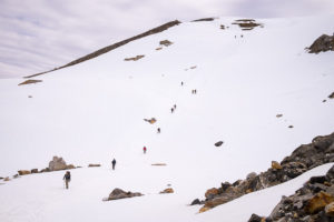 Trekking group running down the steep snowfield