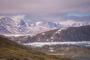 The colourful houses of Kulusuk are dwarfed by the dramatic landscape. Seen while hiking from Kulusuk to Isikajia, East Greenland