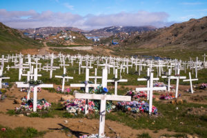 A field of white crosses and plastic flowers marking the graves in the cemetery just outside of Tasiilaq on the way to the Flower Valley