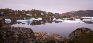 Colourful houses of Kulusuk and pink skies reflected in the perfectly still waters of Kulusuk harbor