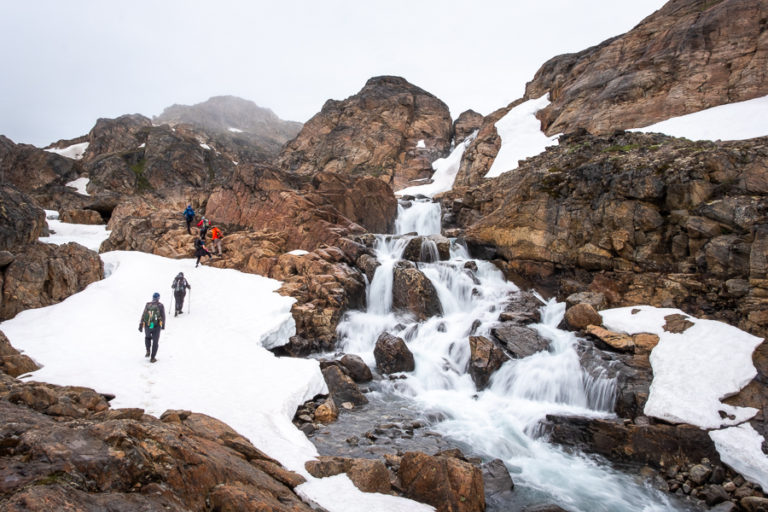 Hiking beside a beautiful waterfall at the start of the Sermilik Way - East Greenland