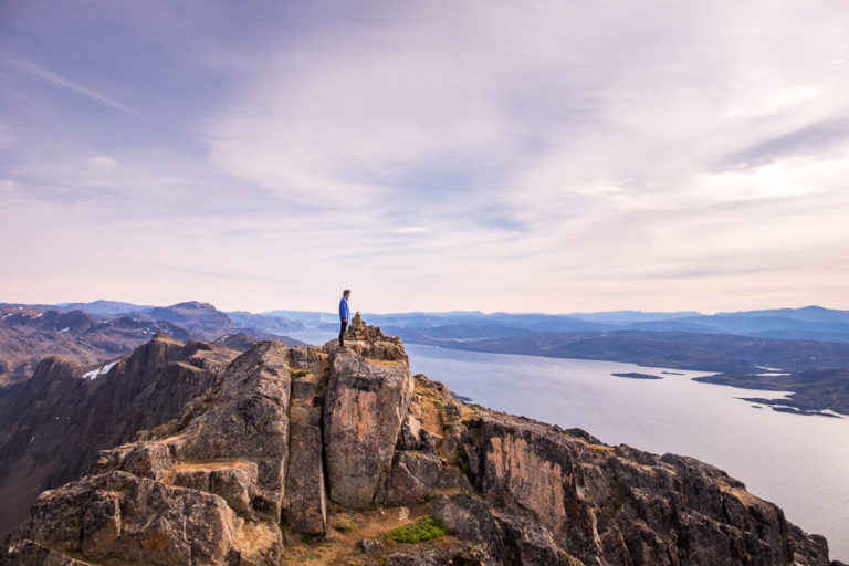 Hiker at the summit of Nasaasaaq Mountain, overlooking the Amerloq Fjord near Sisimiut, West Greenland