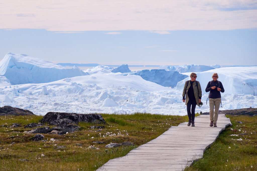 Visitors walking along a boardwalk near Ilulissat Icefjord, showing managed access and visitor infrastructure.