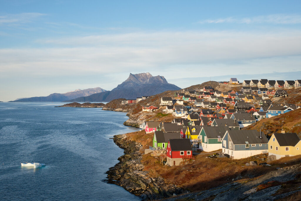Nuuk in Greenland with colourful housing along the shoreline and mountains in the background.