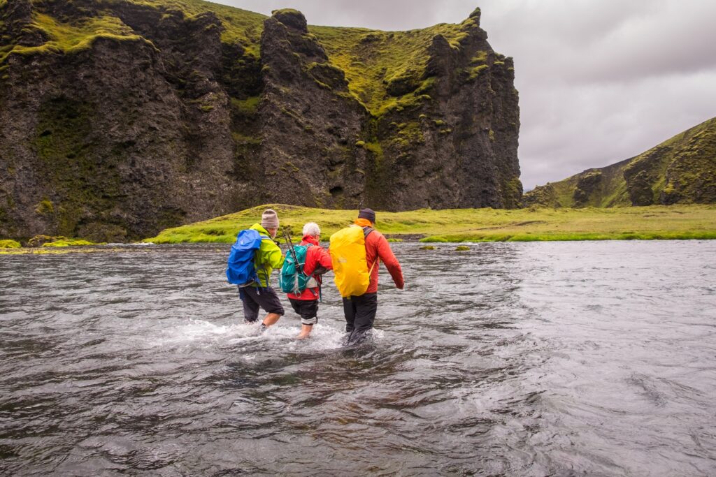 Hikers supporting each other at a river crossing encountered during a multi-day guided hike in Iceland
